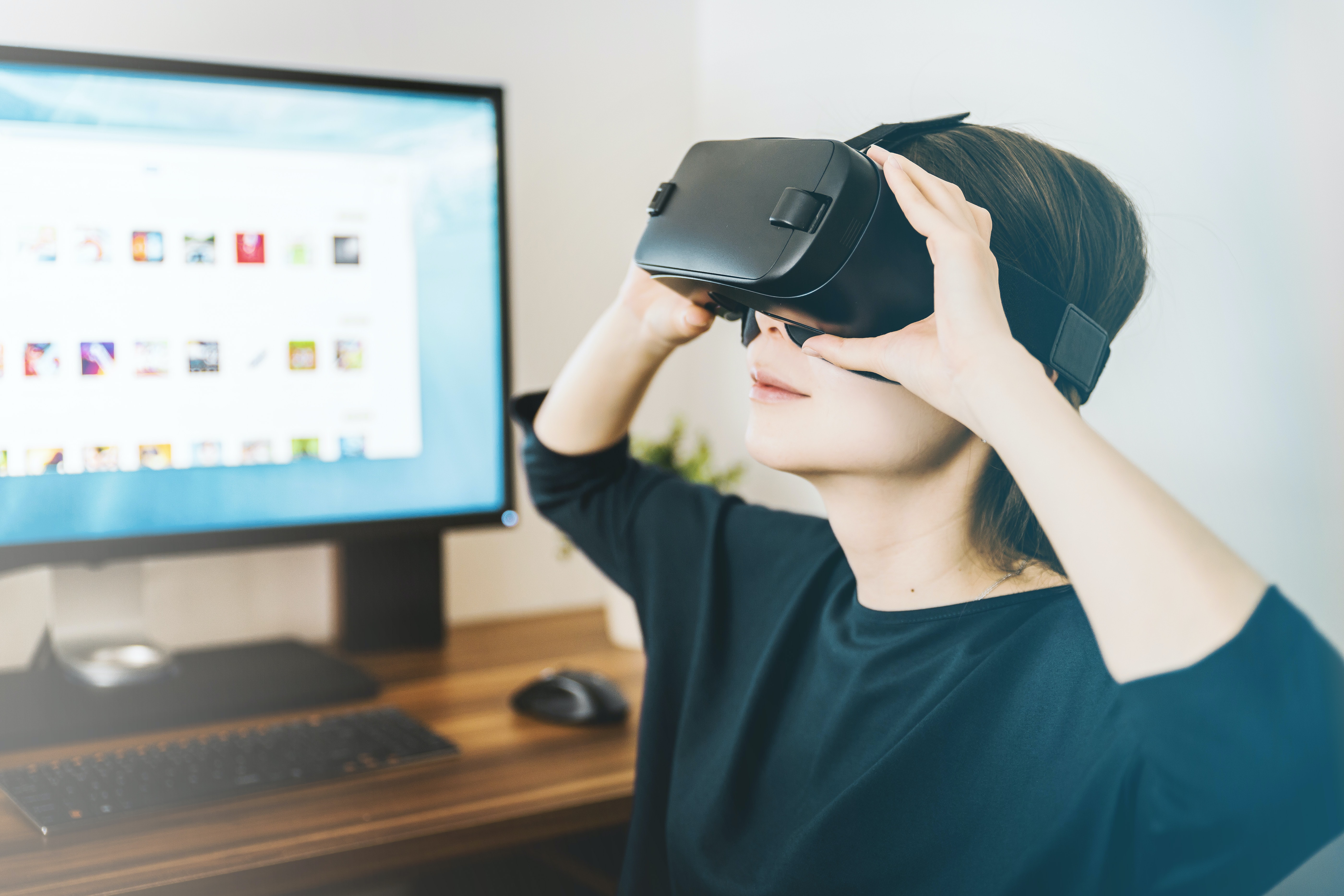 a woman adjusting a vr headset while seated at a computer