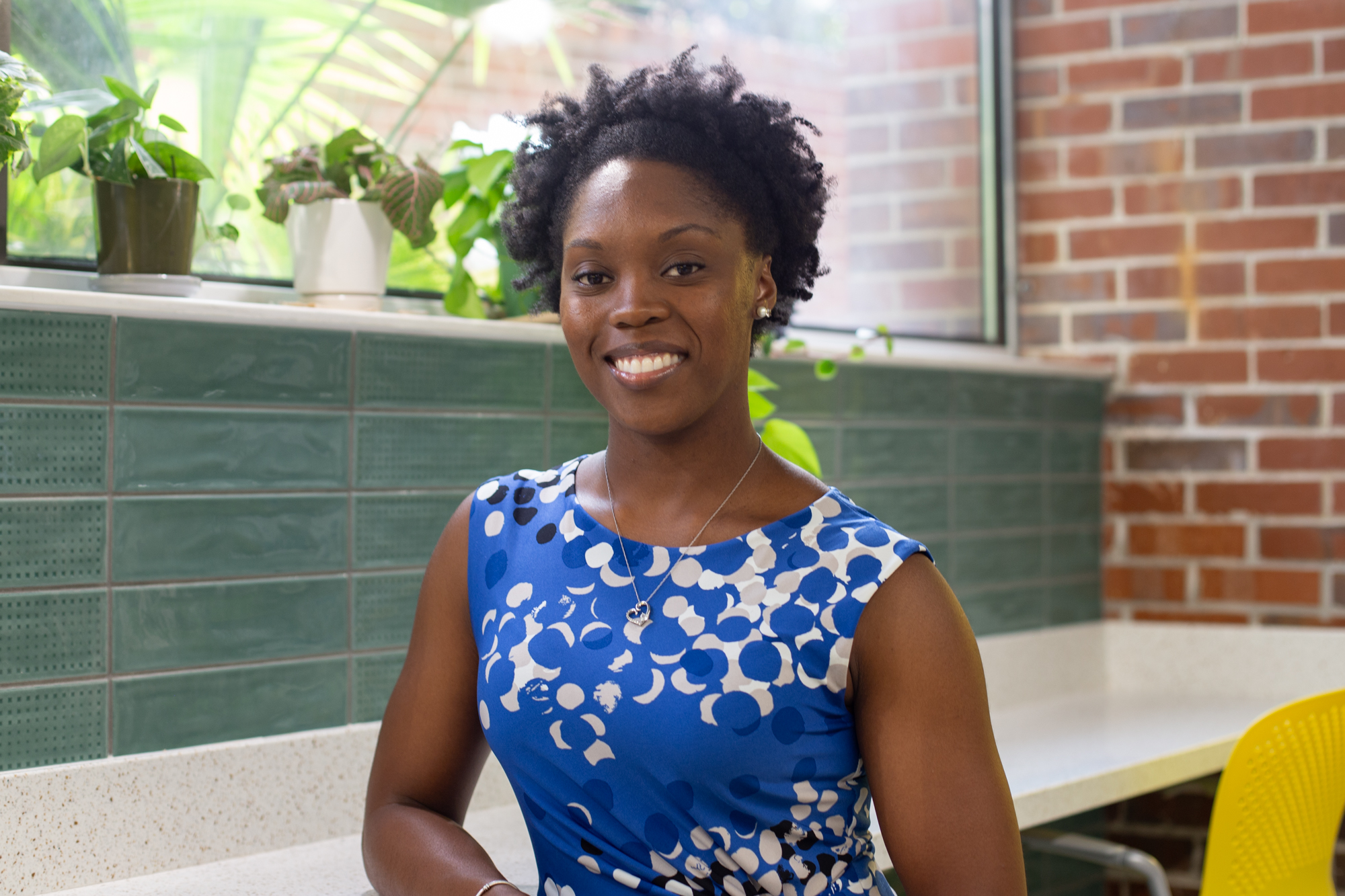 African American women black hair wearing a blue dress with polka dots and floral prints.